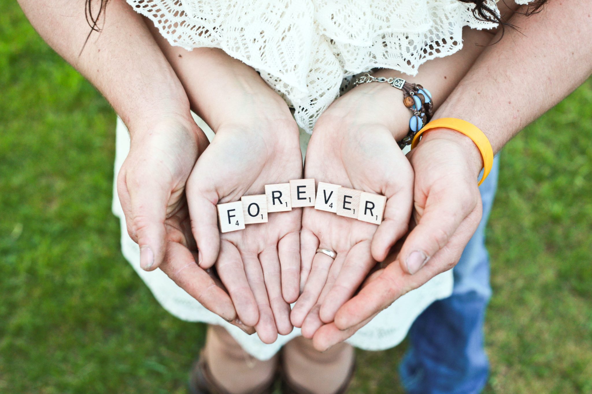 Couple holding Scrabble letters that spell FOREVER. Games